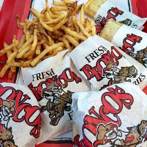A red tray filled with crispy French fries and several wrapped sandwiches from a restaurant called "Bronco's."