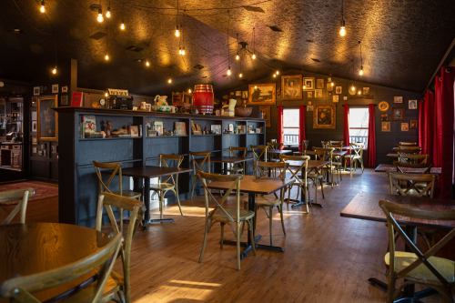 Cozy restaurant interior with wooden tables, chairs, and warm lighting, featuring framed photos on dark walls.
