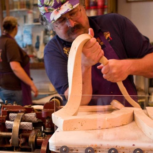 A person demonstrates shaping dough in a kitchen, with tools and ingredients visible in the background.