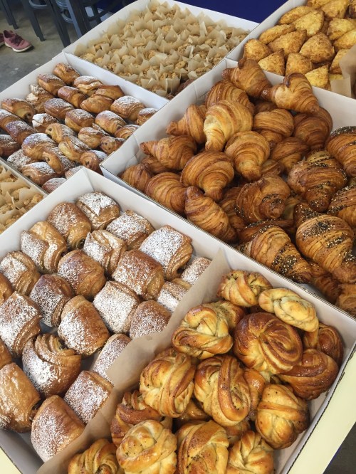 A variety of baked goods displayed in boxes, including croissants, pastries, and sweet rolls.