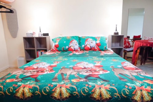 A festive bedroom featuring a Santa-themed bedspread with decorative pillows and a cozy, cheerful atmosphere.