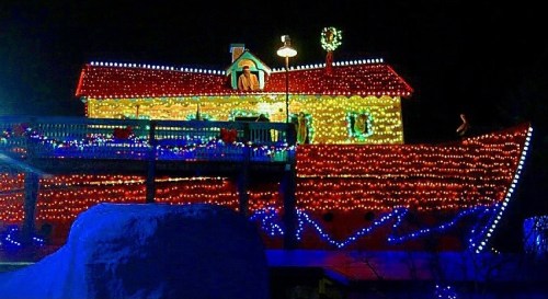 A brightly lit house decorated with colorful Christmas lights, featuring a festive wreath and holiday decorations.