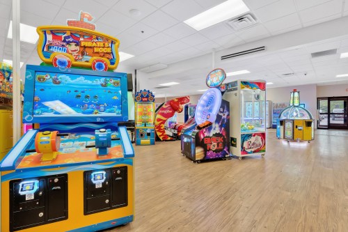 A bright arcade featuring various games, including a pirate-themed machine and a ticket redemption booth.