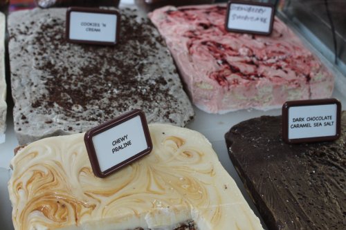 A display of various ice cream flavors, including cookies 'n cream, chewy praline, and dark chocolate caramel sea salt.