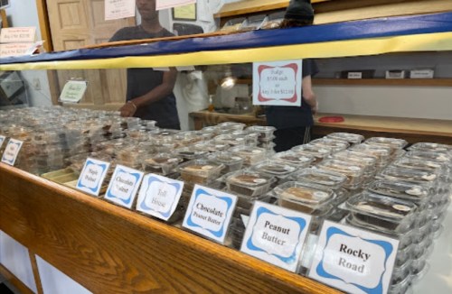 A display case filled with various desserts in clear containers, labeled with flavors like Rocky Road and Peanut Butter.
