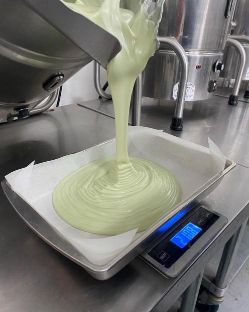 A green batter is being poured into a tray on a digital scale in a kitchen setting.