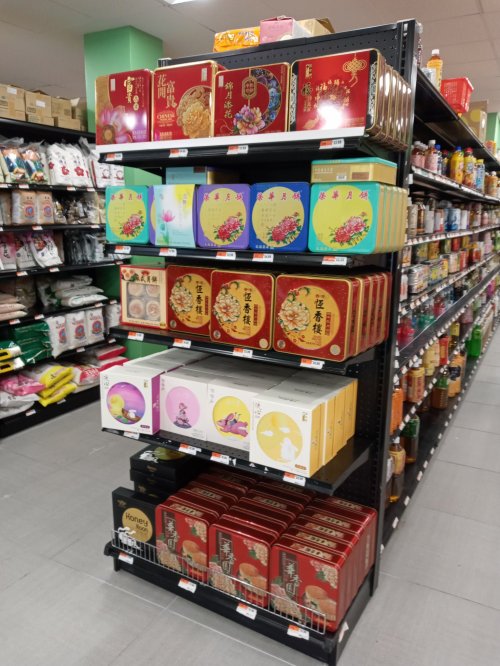 A store shelf displaying various colorful boxes of mooncakes and snacks, with products neatly arranged.