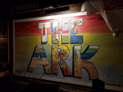 Colorful mural reading "Greetings from THE ARK" with vibrant designs and patterns on a textured wall.