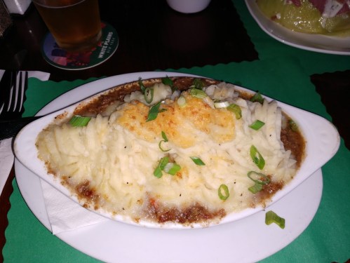 A dish of shepherd's pie topped with mashed potatoes and green onions, served in a white oval dish.
