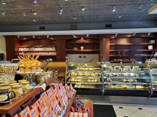 A cozy bakery interior featuring a display case of pastries, breads, and a decorative shelf with baked goods.
