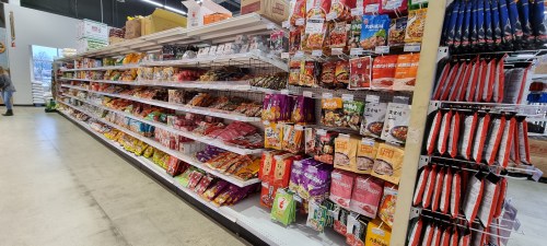 A grocery store aisle filled with various packaged snacks and food items on shelves.