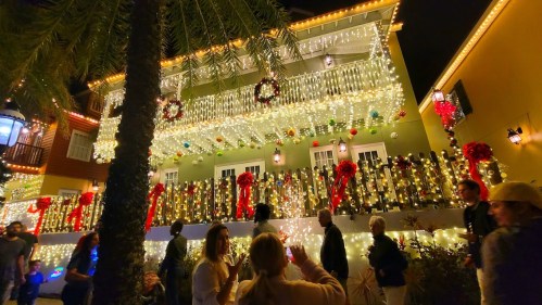 A beautifully decorated building with festive lights and wreaths, surrounded by people enjoying the holiday atmosphere.