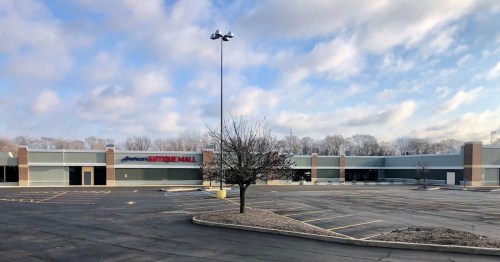 A mostly empty parking lot in front of an antique mall under a cloudy sky.