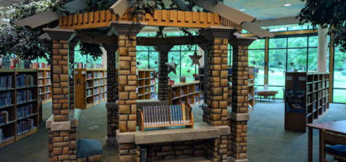 A cozy library nook with stone pillars, bookshelves, and large windows overlooking greenery.