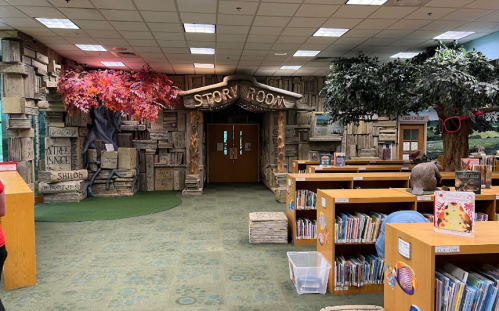 A whimsical library story room entrance with tree decorations and bookshelves in a cozy, inviting setting.