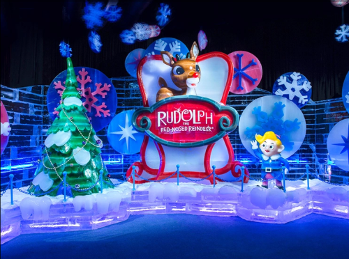Colorful holiday display featuring a reindeer, a Christmas tree, and a cheerful elf, surrounded by snowflakes and ice decorations.