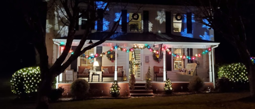 A beautifully decorated house at night, featuring colorful lights and snowflake projections on the facade.