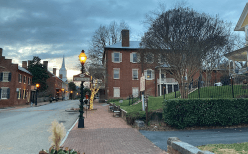 A quiet street lined with historic brick buildings, a lamppost, and trees under a cloudy sky.