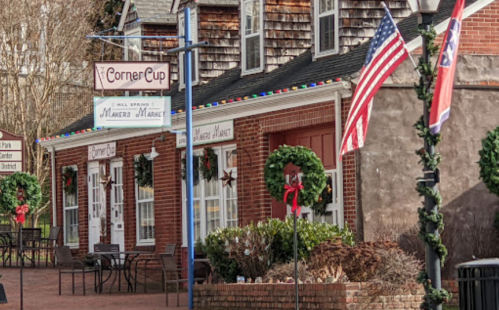 A charming storefront with wreaths and festive decorations, featuring American flags and a cozy outdoor seating area.