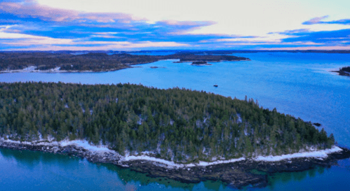 Aerial view of a serene coastal landscape with lush green islands and calm blue waters under a cloudy sky.
