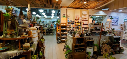 A cozy store interior filled with shelves of various home goods, decor, and kitchen items, warmly lit and inviting.