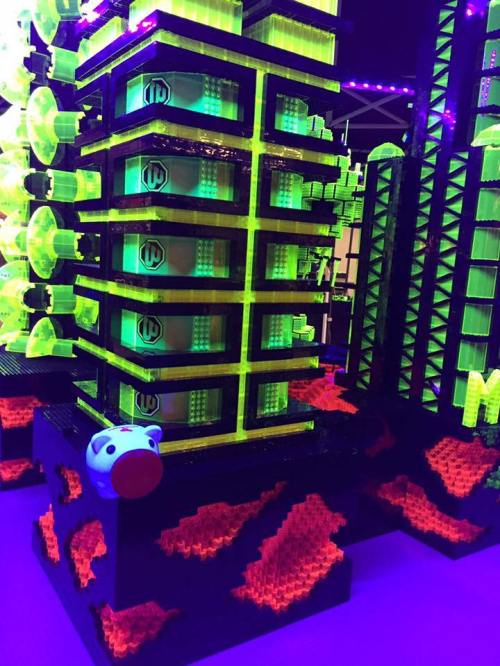 A colorful, futuristic building made of neon green and black blocks, with a pig figure at the base and a vibrant background.