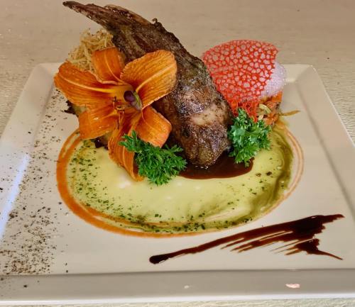 A beautifully plated dish featuring grilled meat, vibrant garnishes, and colorful sauces on a white plate.