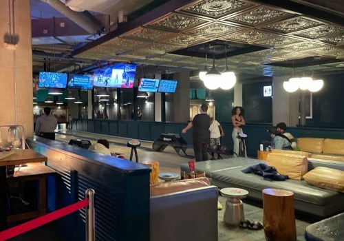 A modern lounge with seating, screens displaying content, and people socializing in a stylish interior.