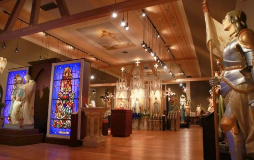 A spacious interior featuring stained glass, religious statues, and ornate decorations in a museum setting.