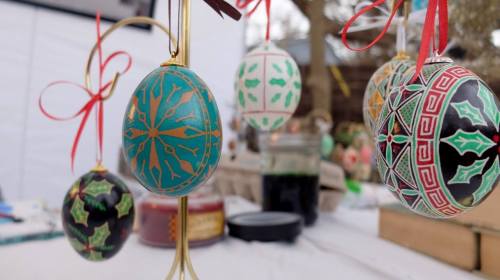 Colorful decorative Easter eggs hanging with ribbons, featuring intricate patterns and designs, displayed at a festive event.