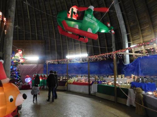 A festive indoor scene with inflatable decorations, a Christmas tree, and families admiring holiday displays.