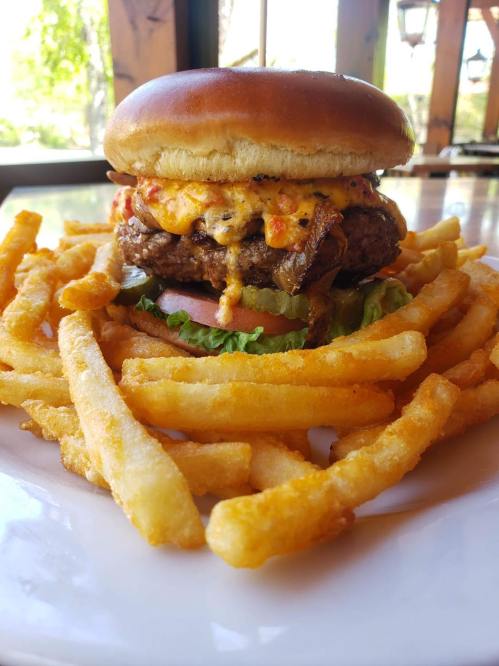 A juicy burger topped with melted cheese, served on a bun with lettuce and tomato, surrounded by golden French fries.