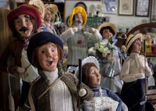 A collection of vintage dolls dressed in various outfits, some singing, in a charming display setting.