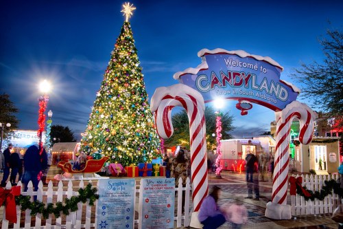 A festive entrance to Candyland, featuring a large Christmas tree, candy cane decorations, and visitors enjoying the holiday scene.