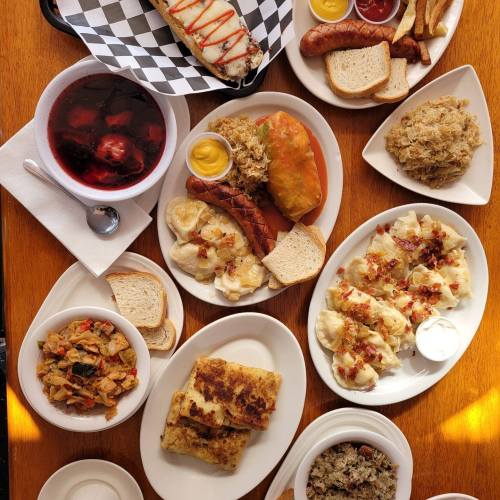 A variety of dishes including sausages, bread, salads, and desserts arranged on a wooden table.