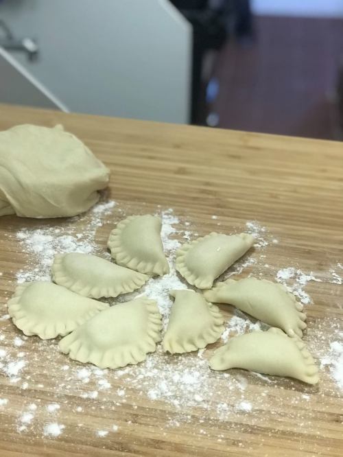 Dough and uncooked dumplings arranged on a floured wooden surface.