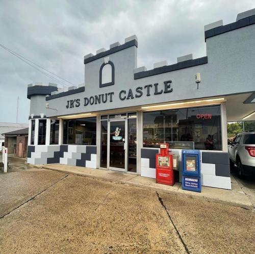 Exterior of JR's Donut Castle, a castle-themed donut shop with large windows and an "Open" sign.