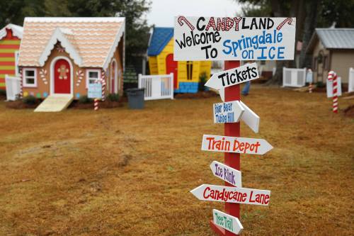 Colorful Candyland-themed decorations with a signpost pointing to various attractions in a festive outdoor setting.