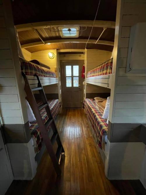 Interior of a cozy cabin with two sets of bunk beds, wooden floors, and a door leading outside.