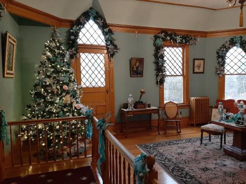 Cozy room decorated for the holidays, featuring a Christmas tree, vintage furniture, and festive garlands.