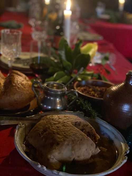 A festive table setting with a roasted turkey, gravy, and side dishes, illuminated by candlelight.