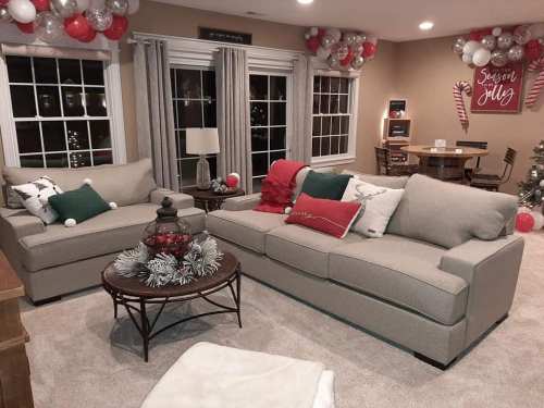 Cozy living room with two sofas, festive decor, and a dining area featuring a Christmas tree and holiday decorations.