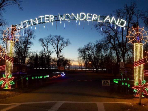 A festive archway reading "Winter Wonderland" adorned with colorful lights, set against a twilight sky.