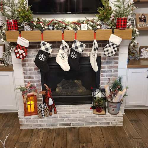 A cozy fireplace decorated for the holidays with stockings, greenery, and festive accents.