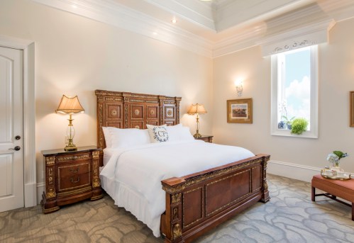Elegant bedroom featuring a wooden bed, bedside tables, lamps, and a window with natural light. Cozy and inviting atmosphere.
