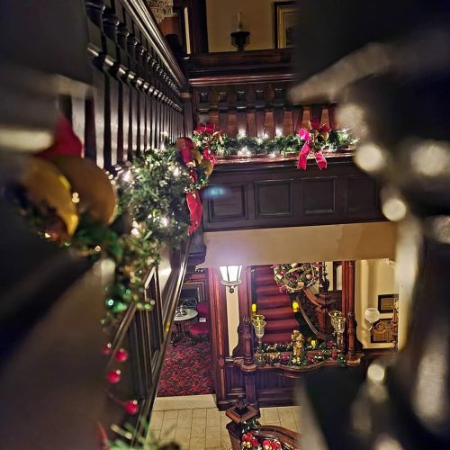 A festive staircase adorned with garlands and bows, leading to a warmly lit entrance decorated for the holidays.