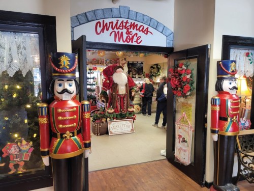 Entrance to a festive shop decorated for Christmas, featuring nutcracker figures and a Santa display inside.