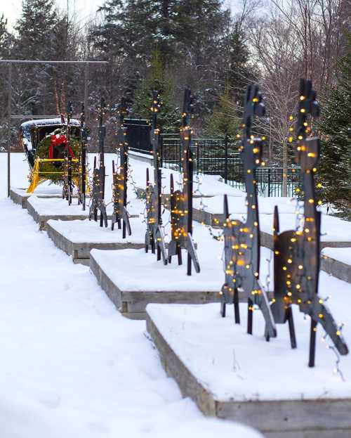 A snowy landscape with wooden structures adorned with lights, and a person in a red outfit near a sled.