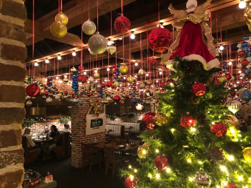A festive restaurant interior decorated with colorful ornaments and a Christmas tree, creating a warm holiday atmosphere.