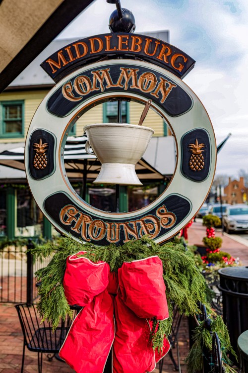 Sign for Middleburg Common Grounds, featuring a decorative wreath and red bows, set in a festive outdoor setting.